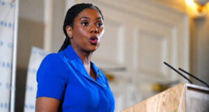 **Kemi Badenoch Facebook page owner speaking at a podium during a public event**